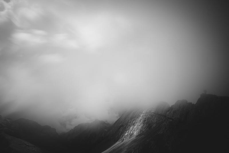 A black and white image of a mountain covered in clouds